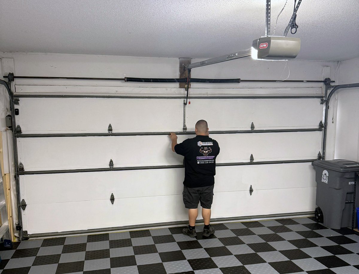 Technician performing a garage door tune-up and safety inspection
